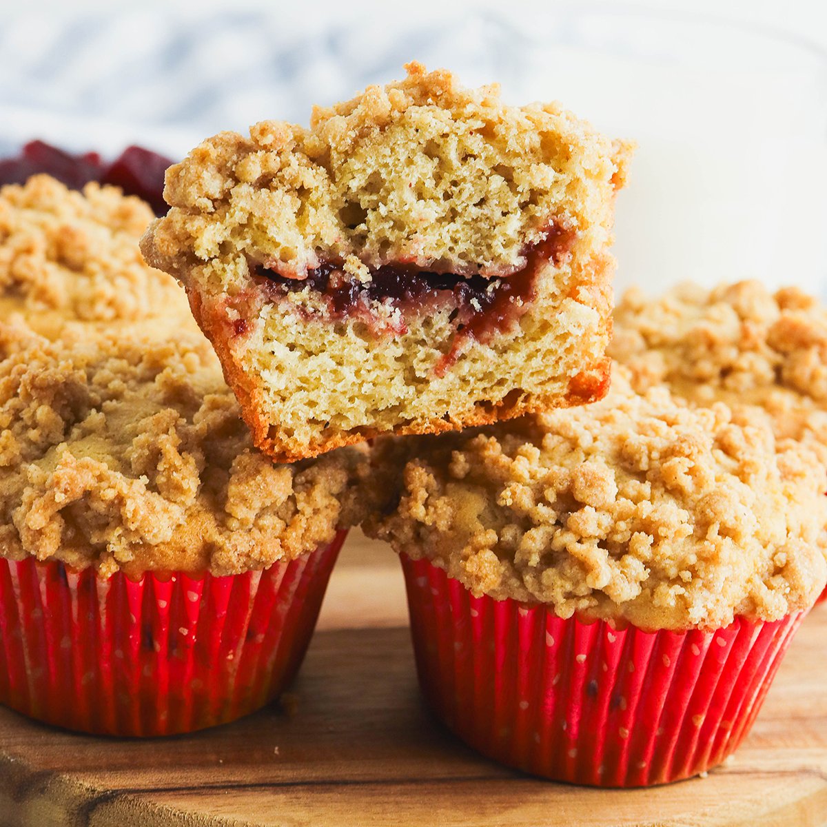 Cranberry Sauce Muffins stacked on a plate with the top muffin cut in half.