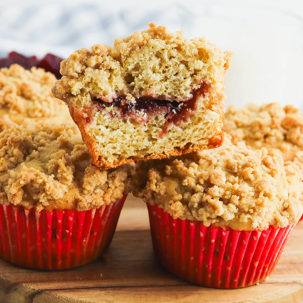 Cranberry Sauce Muffins stacked on a plate with the top muffin cut in half.