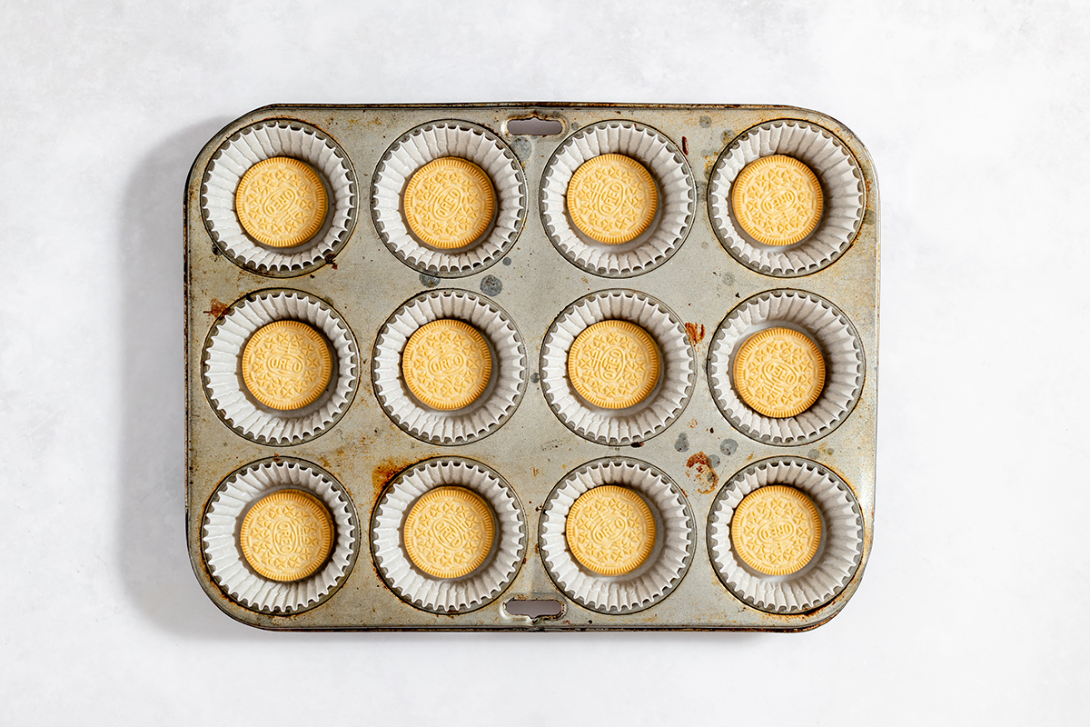 Golden Oreo cookie added to liners in muffin pan.