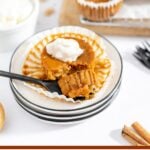 Mini Pumpkin Pie topped with whipped cream on white plate.