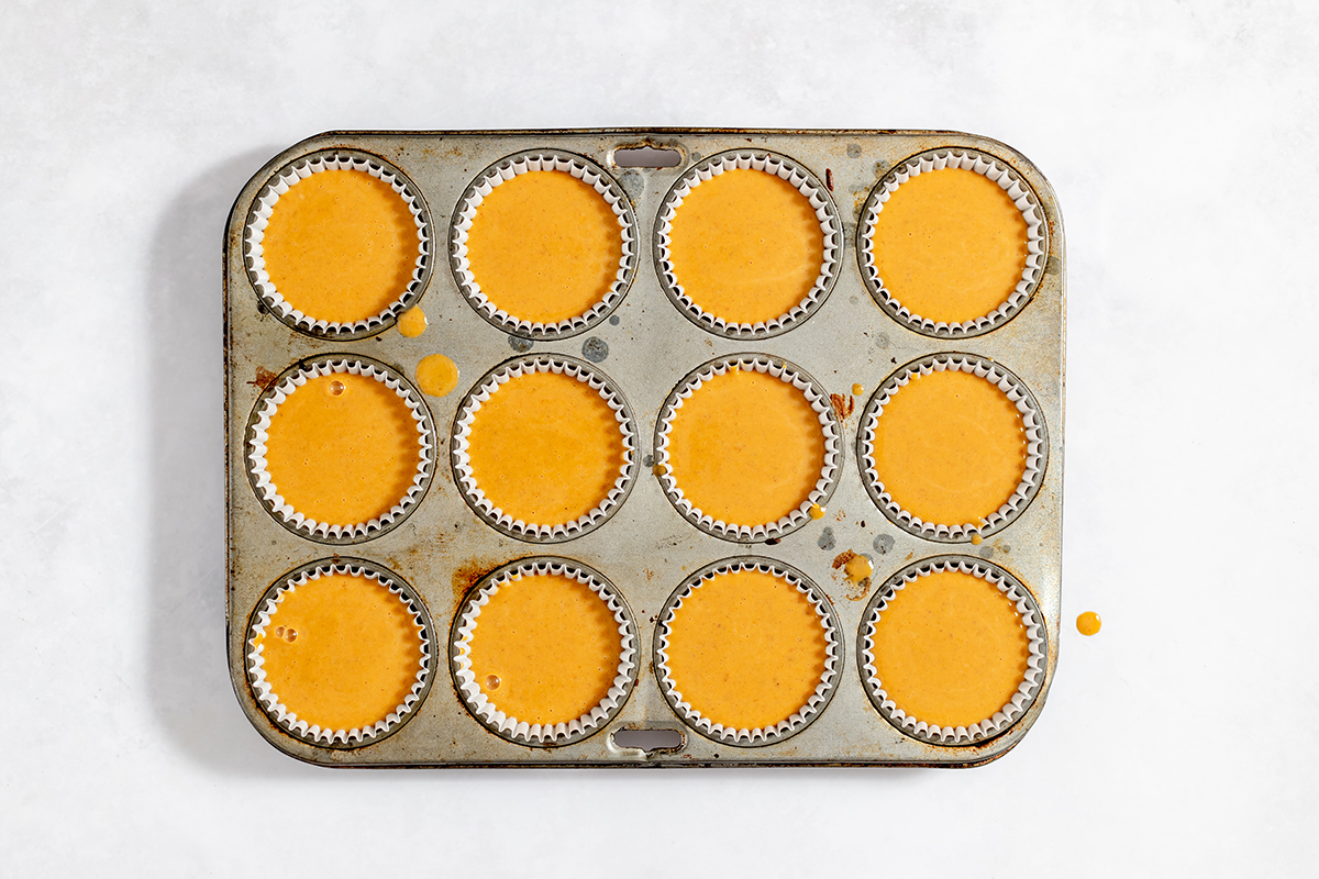 Pumpkin Pie mixture poured over golden oreo cookies in muffin tin.