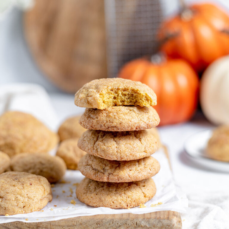 Pumpkin Snickerdoodles stacked together on parchment paper.
