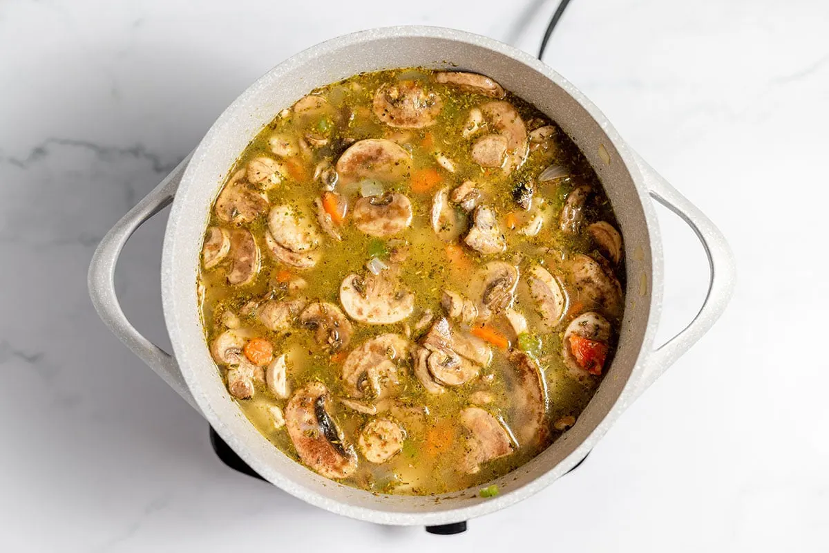 Chicken broth added to chicken and vegetables in large pot.