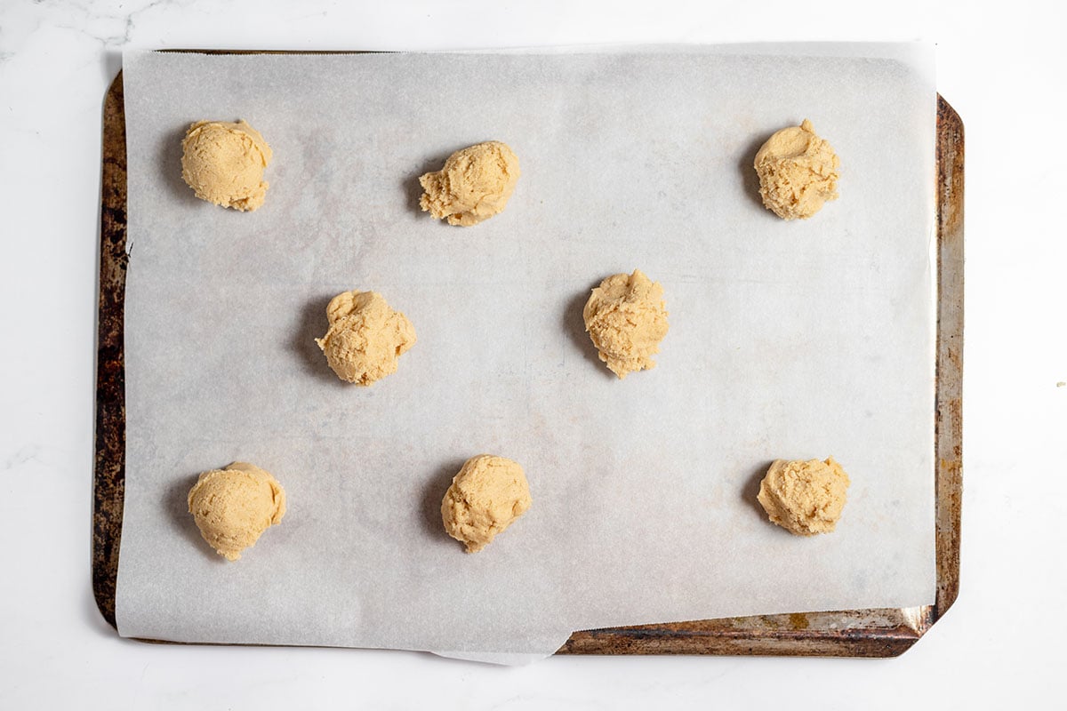 Cookie dough dropped by spoonful onto a cookie sheet.