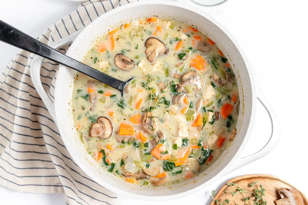 Chicken mushroom soup in large pot with big serving spoon.