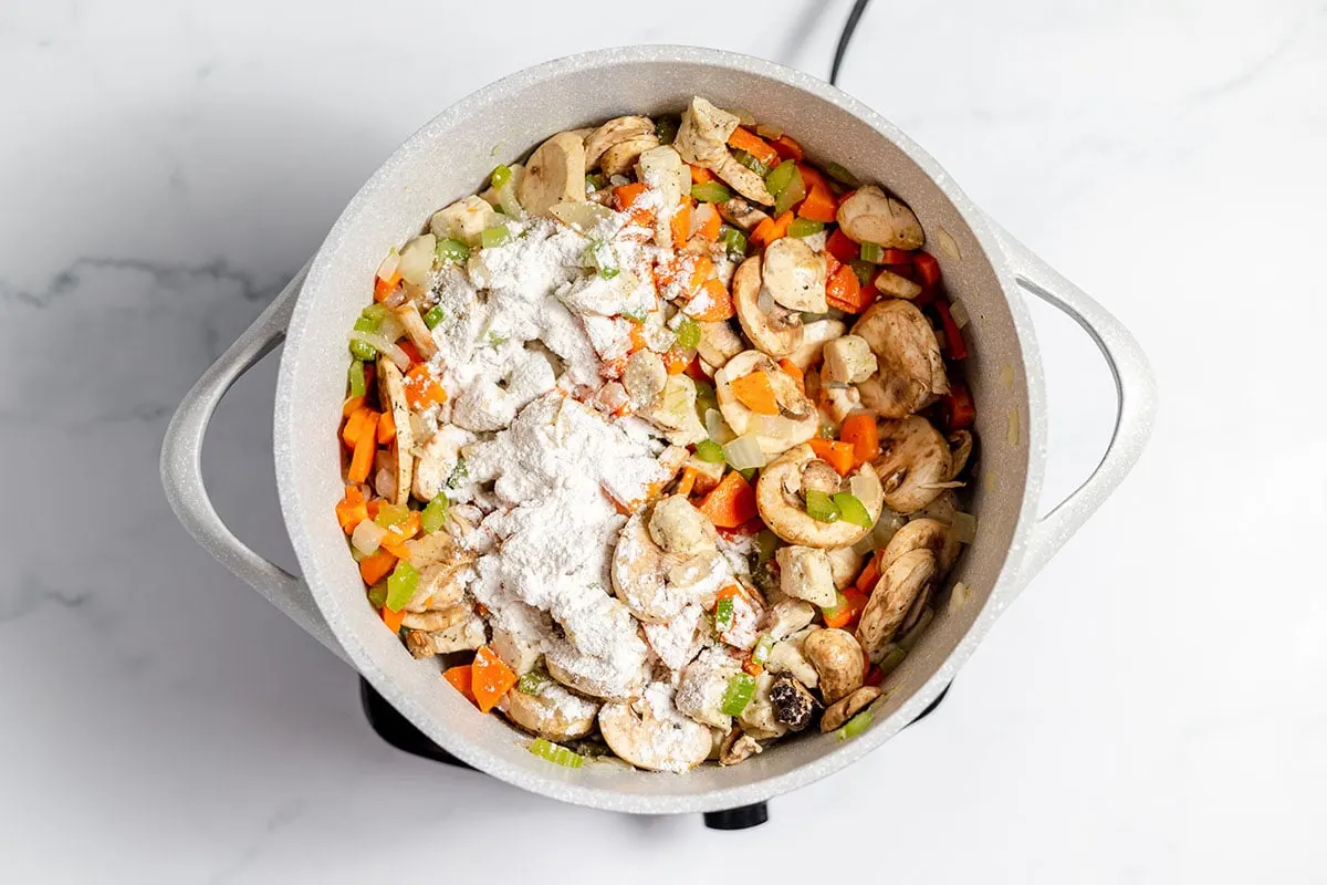 Italian seasoning and flour are added to the chicken and vegetables in large pot.