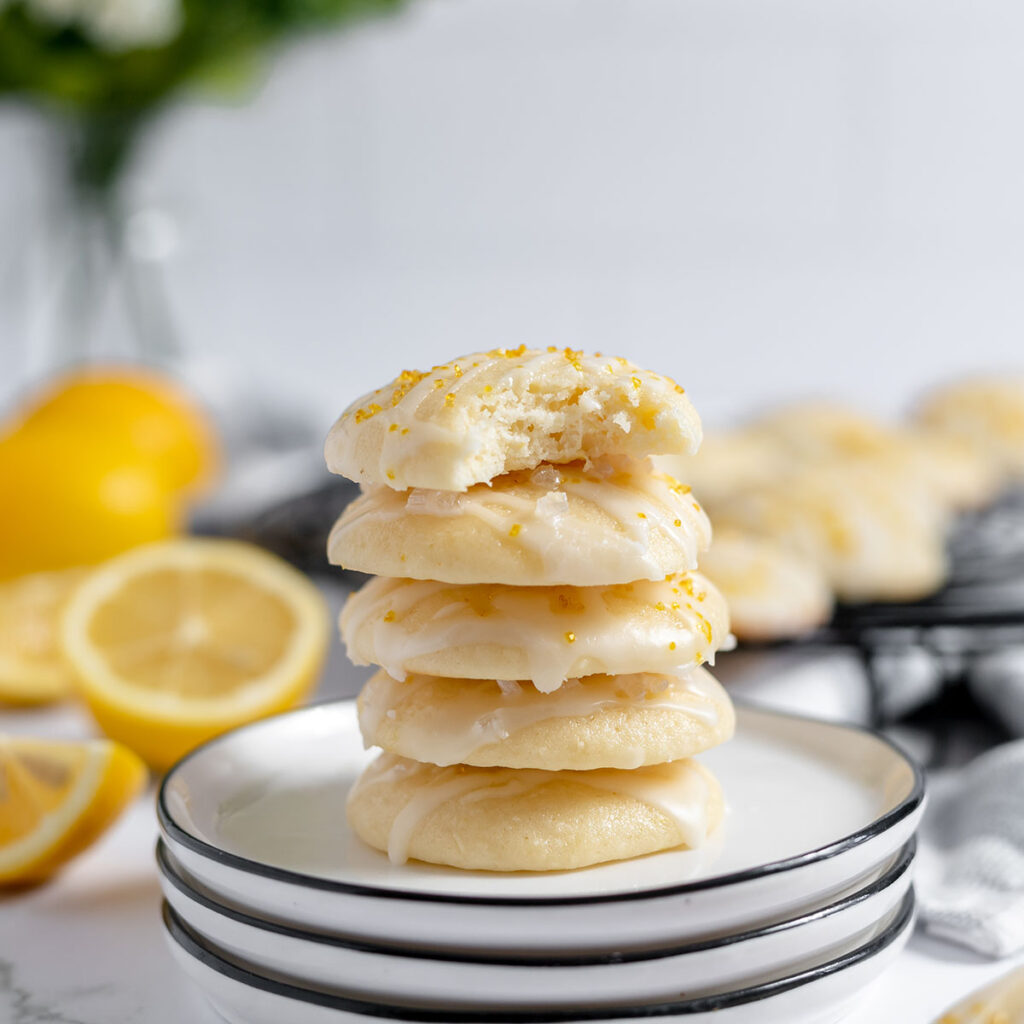 Four Lemon Ricotta Cookies stacked on white plate.