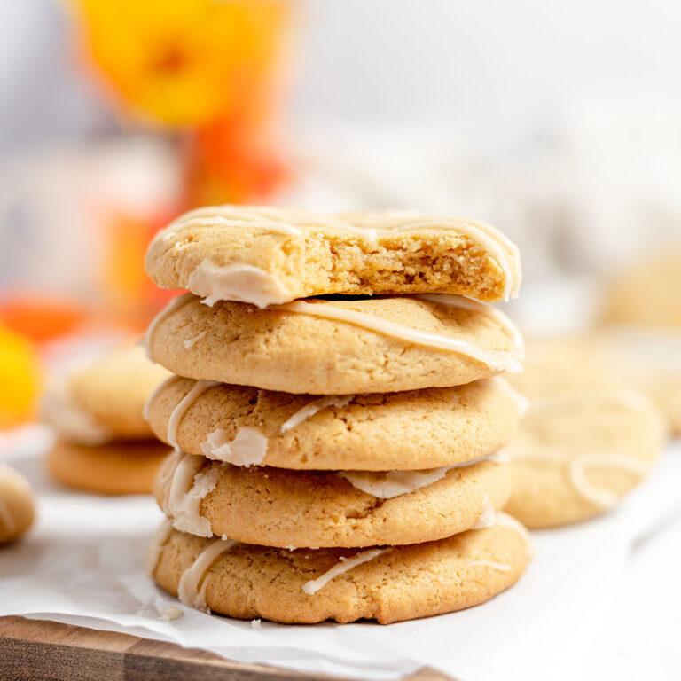Maple Brown Sugar Cookies are stacked on a white parchment line wood serving board.