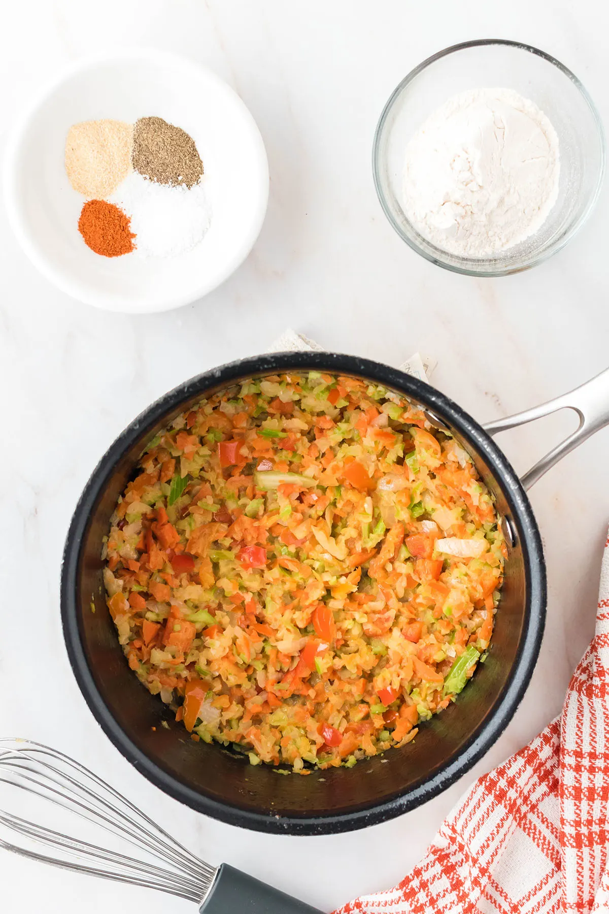 Onion, carrot, celery, and bell pepper in a saucepan.