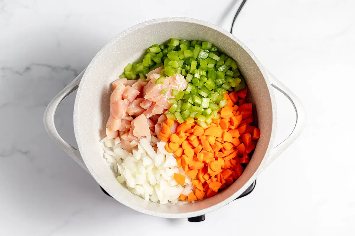 Chicken, onions, carrots, and celery in a large pot.