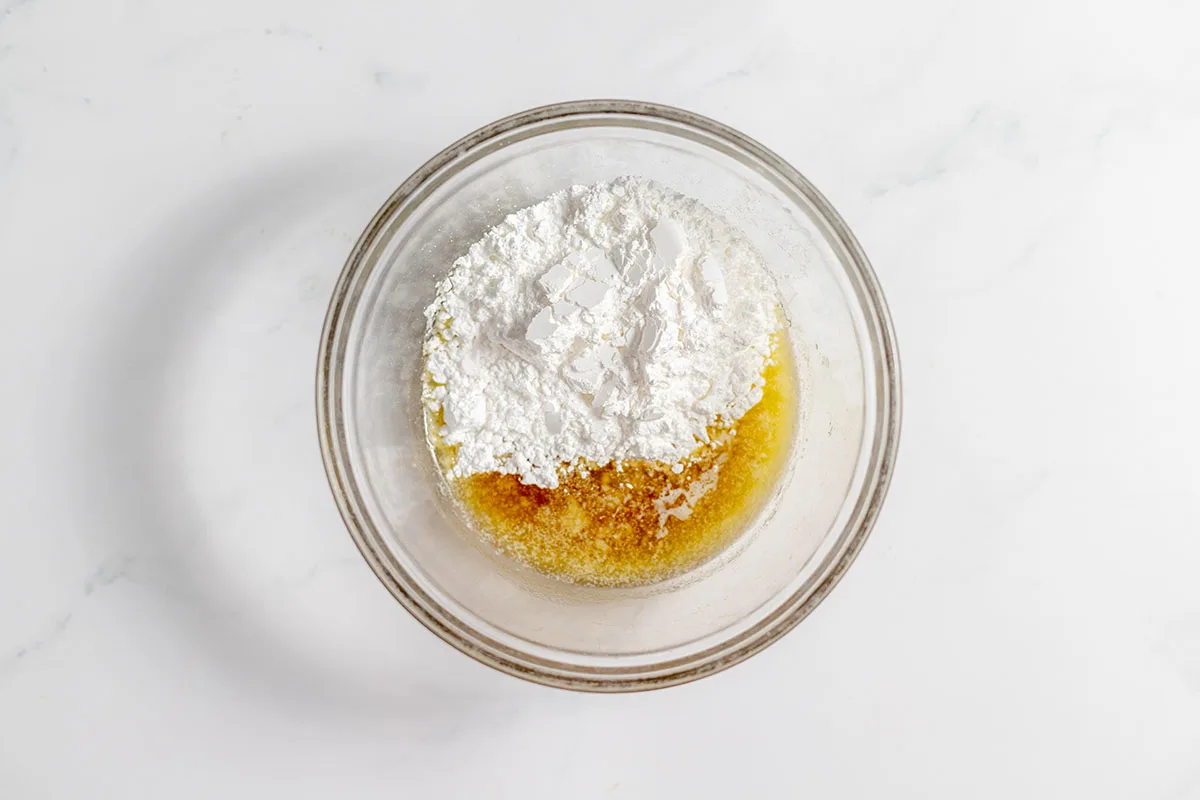 Melted butter, maple syrup, and powdered sugar in a bowl.
