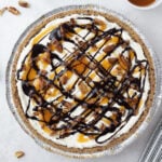 No-bake turtle cheesecake topped with chocolate syrup, caramel syrup, and chopped pecans.