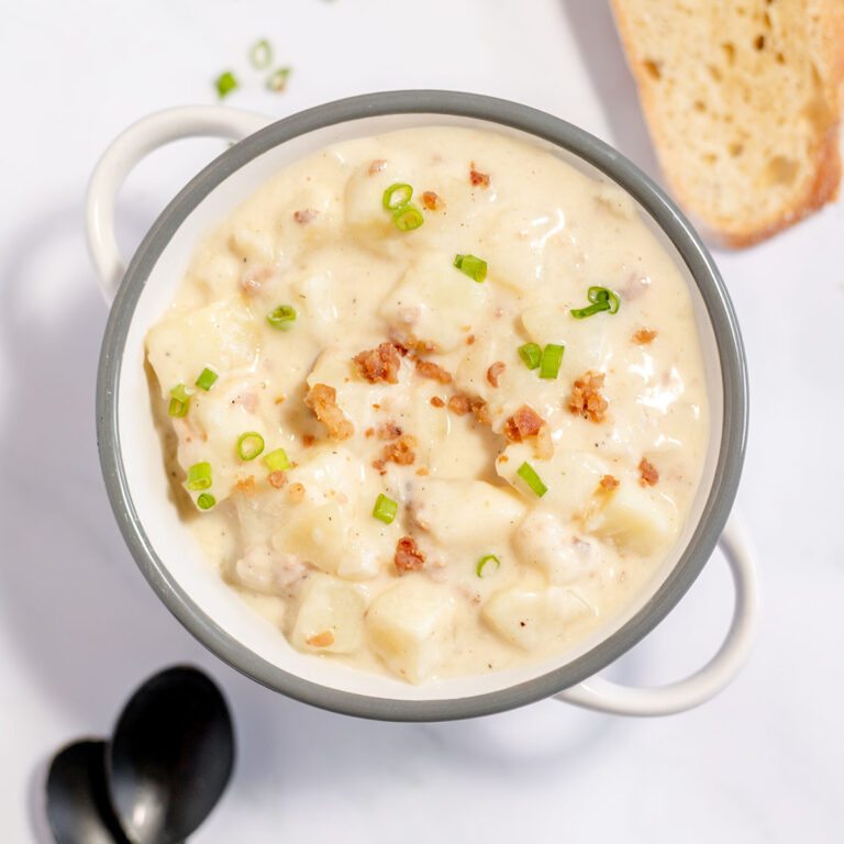 Baked Potato Soup topped with bacon bits and green onions in stock pot.