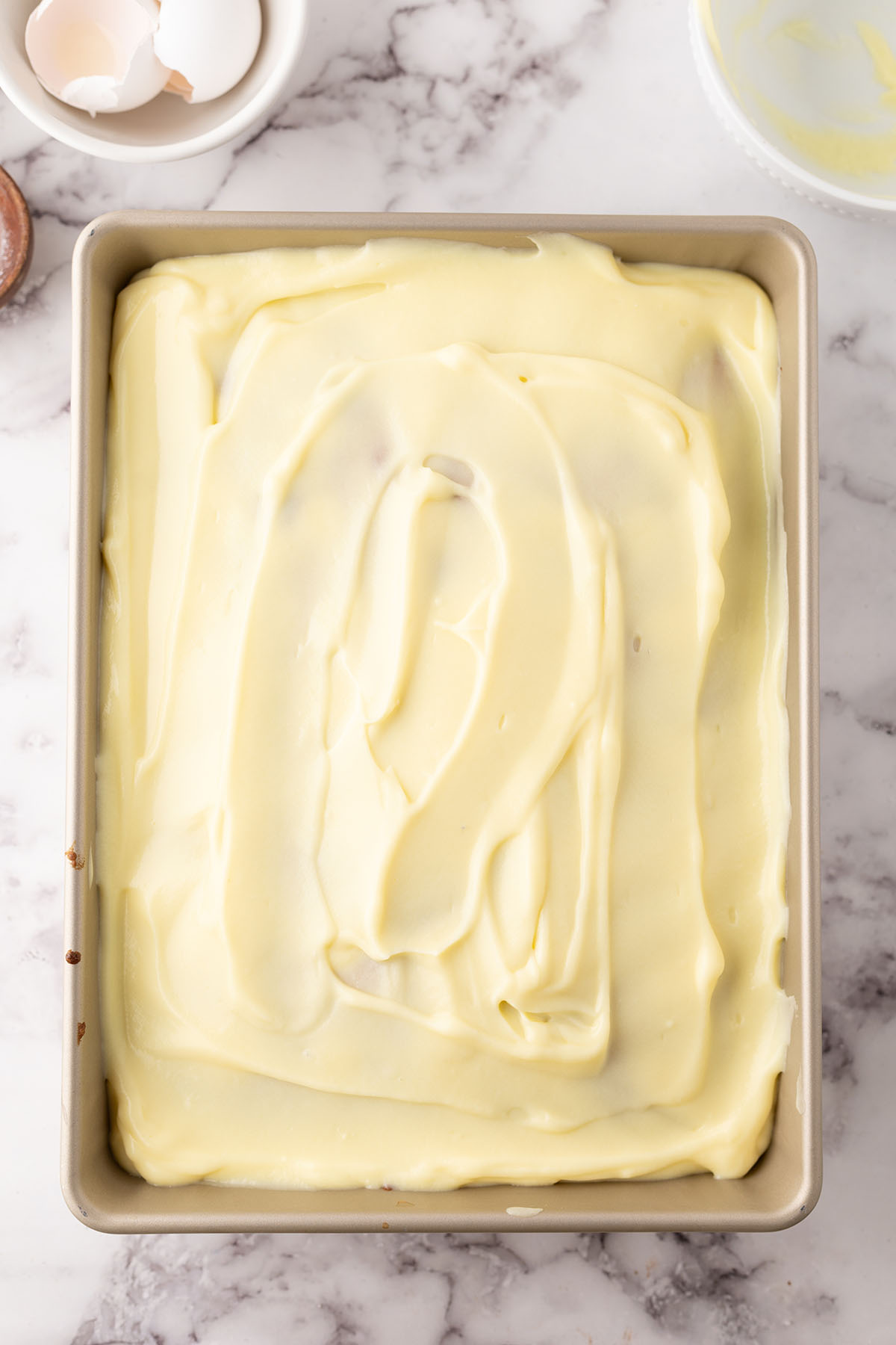 Banana pudding spread over top of cake in baking pan.