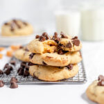 Three Caramel stuffed chocolate chip cookies stacked on wire rack.
