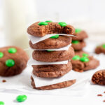 Mint M&M Brownie Cookies stacked on each other with parchment paper between them.