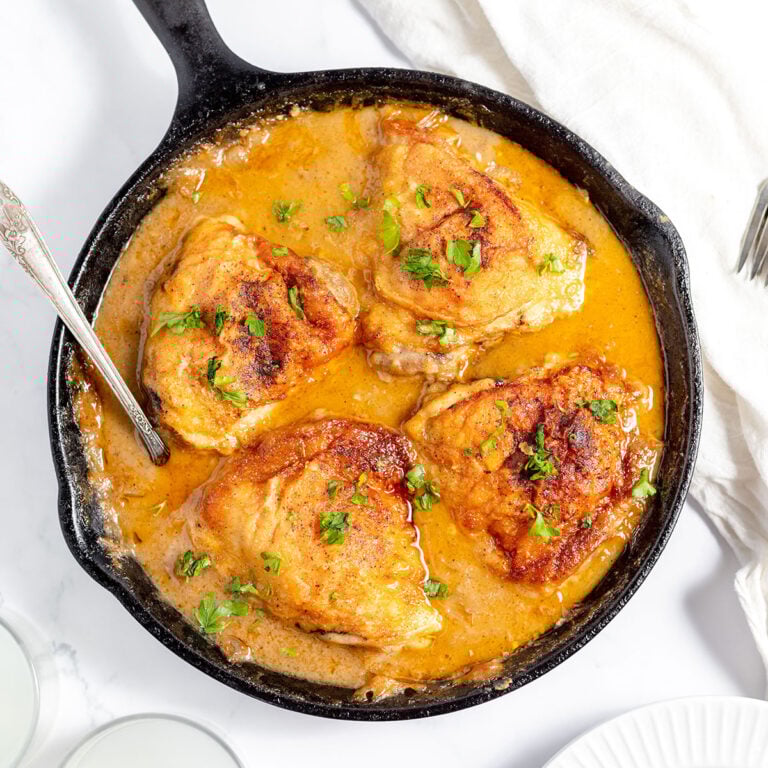 Smothered Chicken Thighs with gravy in a cast iron skillet.