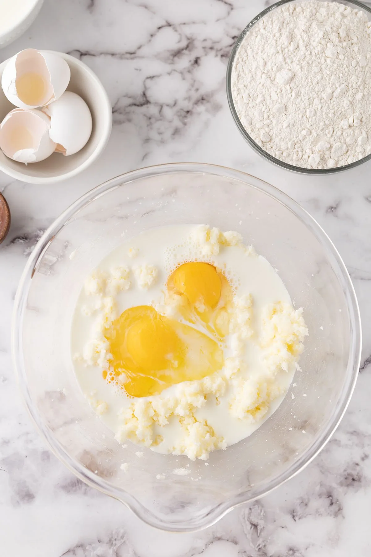 Eggs and heavy cream are added to the creamed butter and sugar in the mixing bowl.