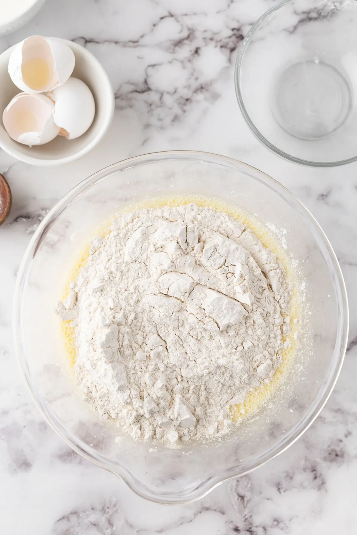 Flour, baking powder, and baking soda are added to the wet ingredients in the mixing bowl.