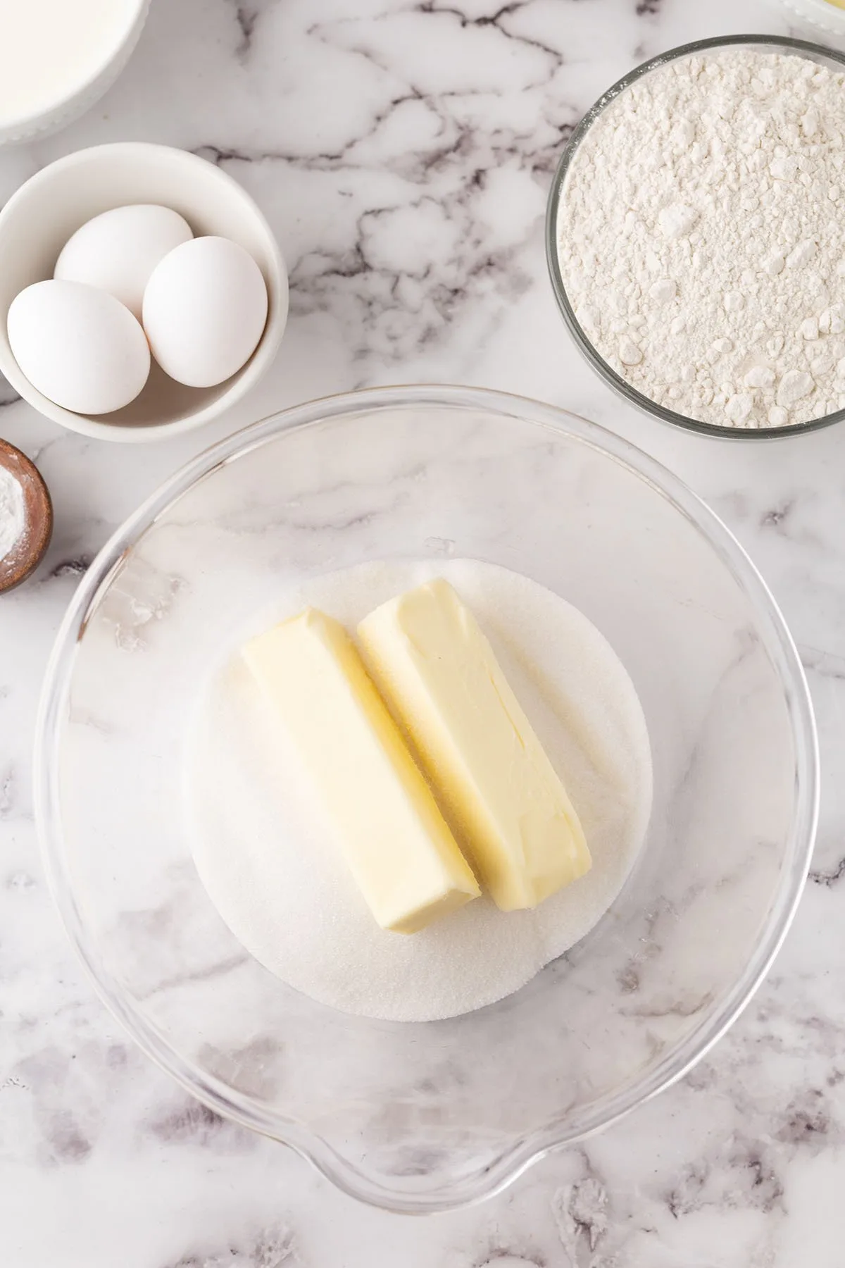 Two sticks of butter and sugar in a mixing bowl.
