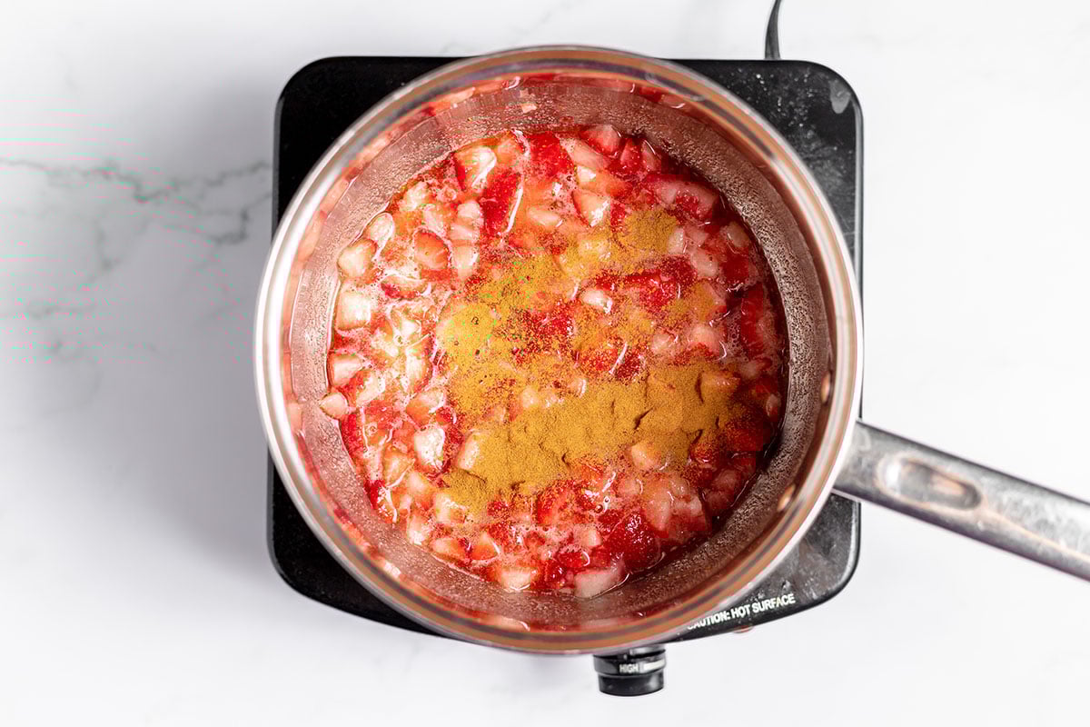 Cinnamon is added to the strawberry sugar mixture in the saucepan.