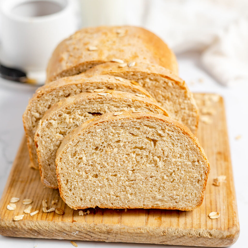 Honey Oat Bread sliced on a wooden serving board.