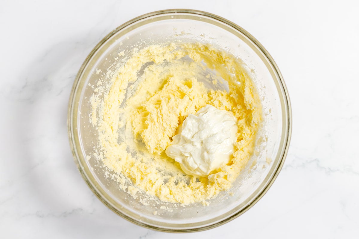 Yogurt is added to butter and sugar in the mixing bowl.