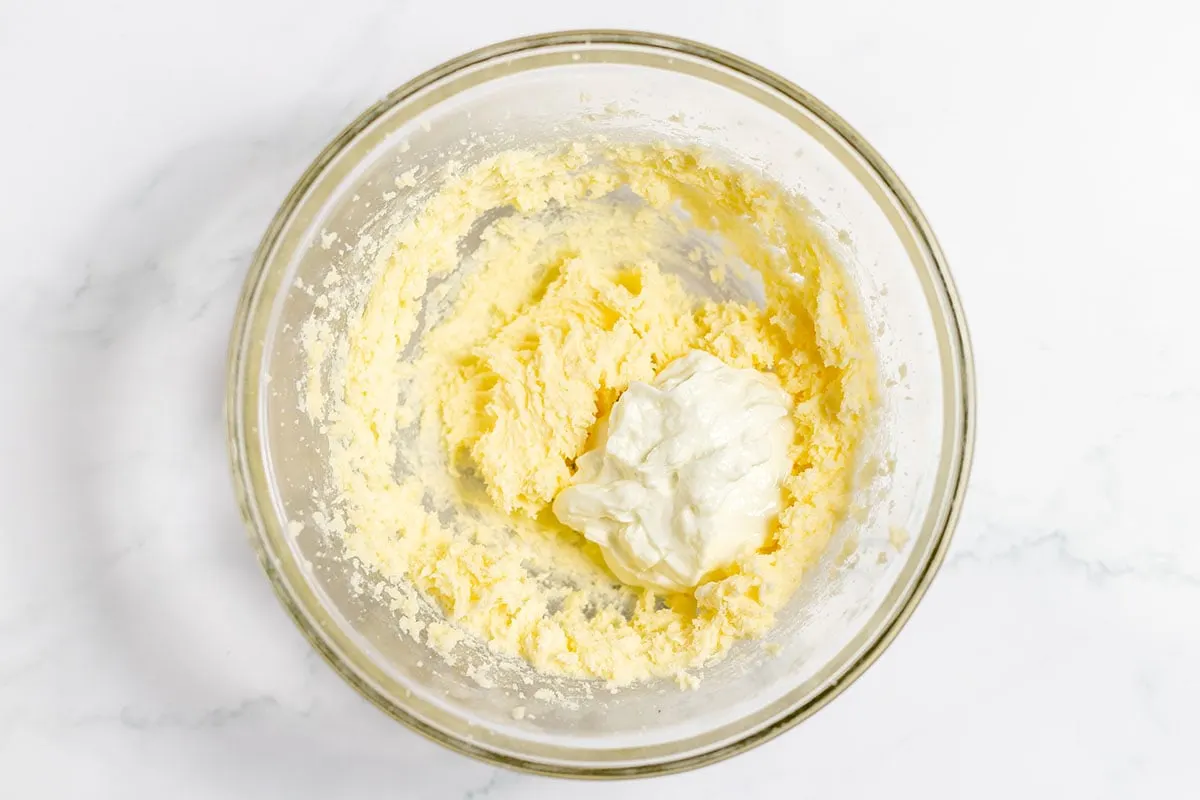 Yogurt is added to butter and sugar in the mixing bowl.