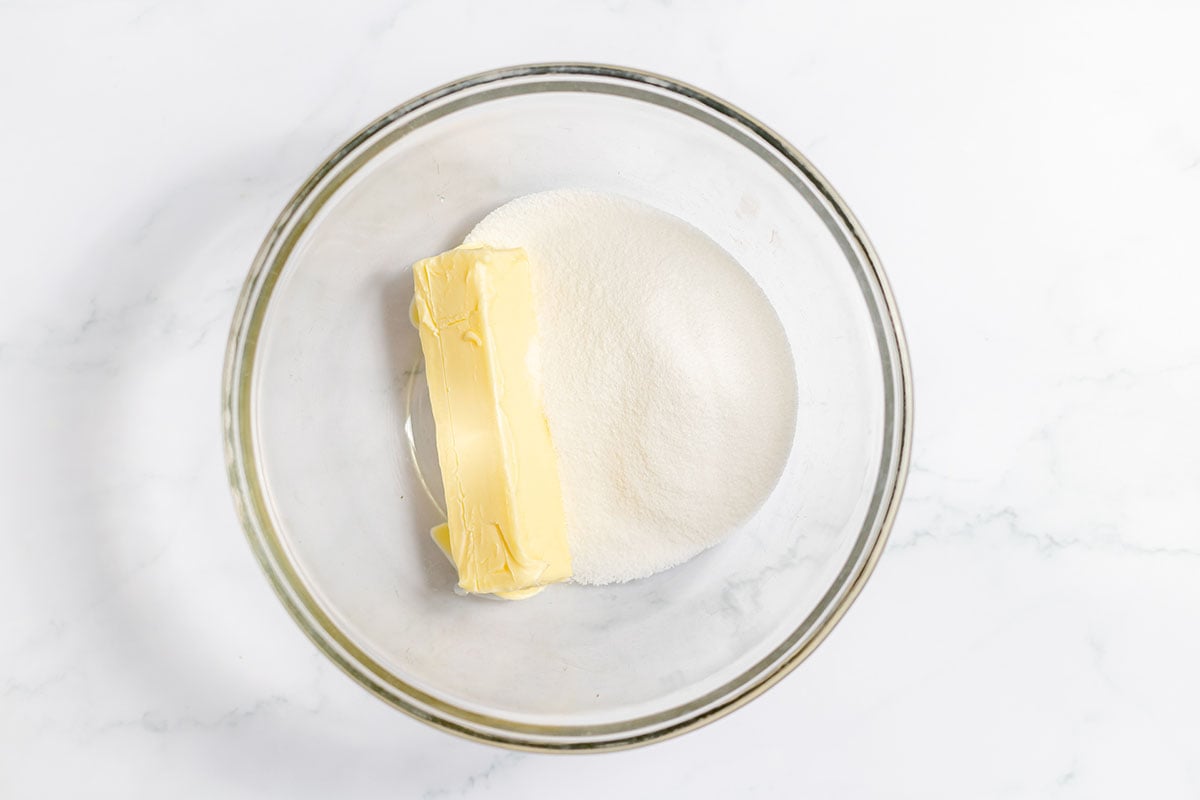 Butter and sugar in a glass mixing bowl.