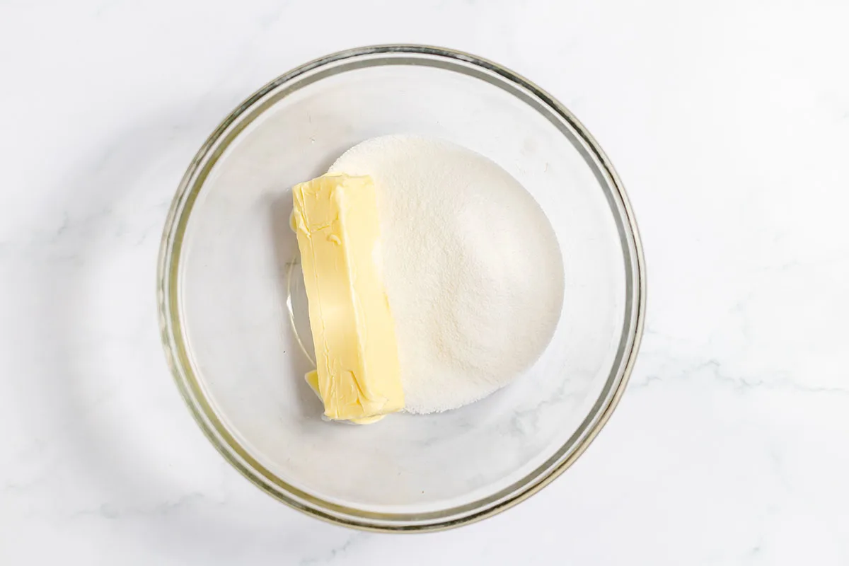 Butter and sugar in a glass mixing bowl.