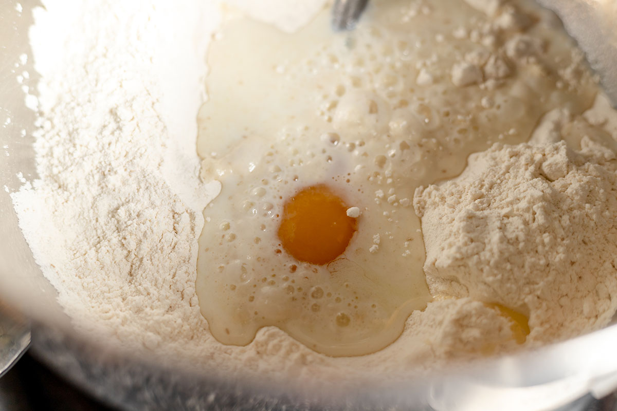 Milk and egg are added to the yeast mixture in the stand mixer bowl.