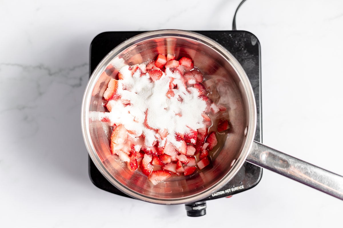 Strawberries and sugar in a sauce pan.
