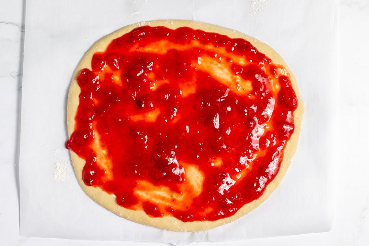 Strawberry filling spread over rolled-out dough.