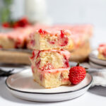 Three Strawberry Lemon Blondies stacked on a white plate.