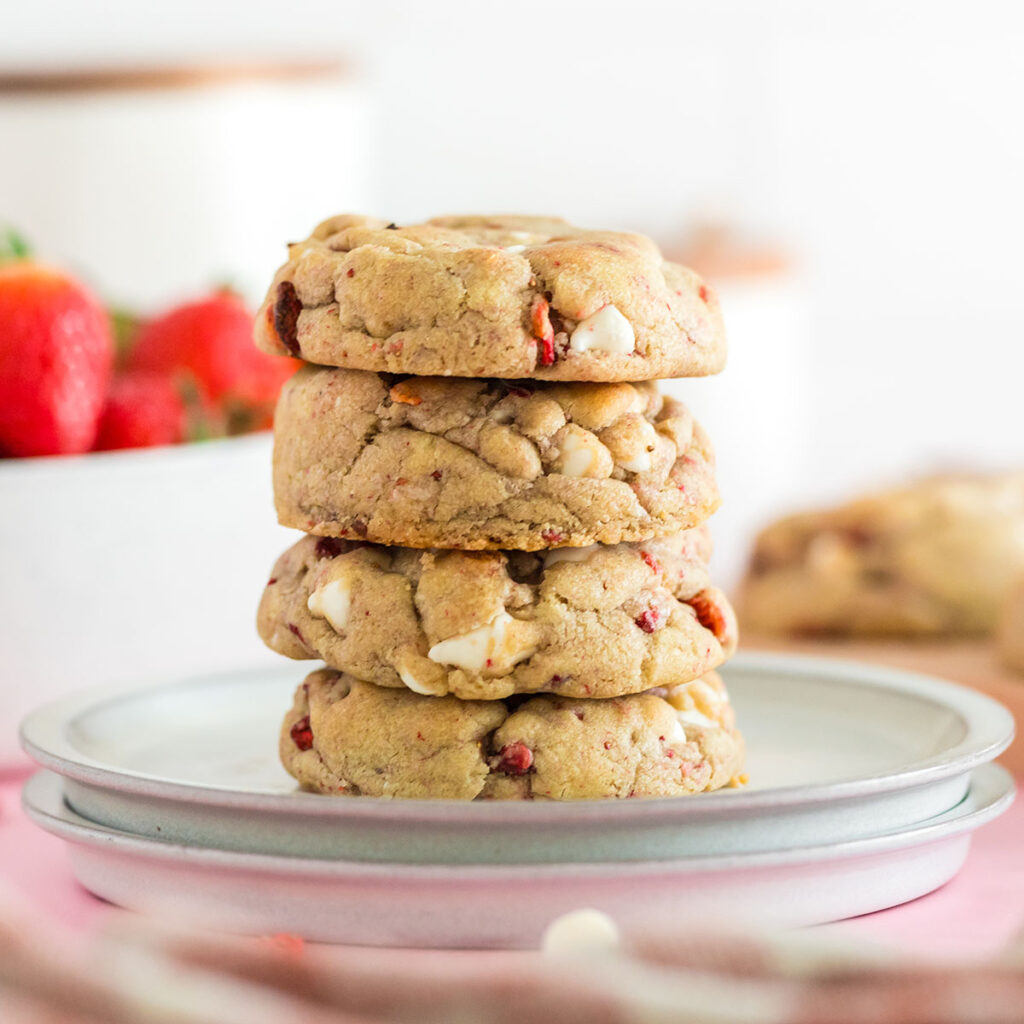 Four Strawberry White Chocolate Chip Cookies stacked on a plate.