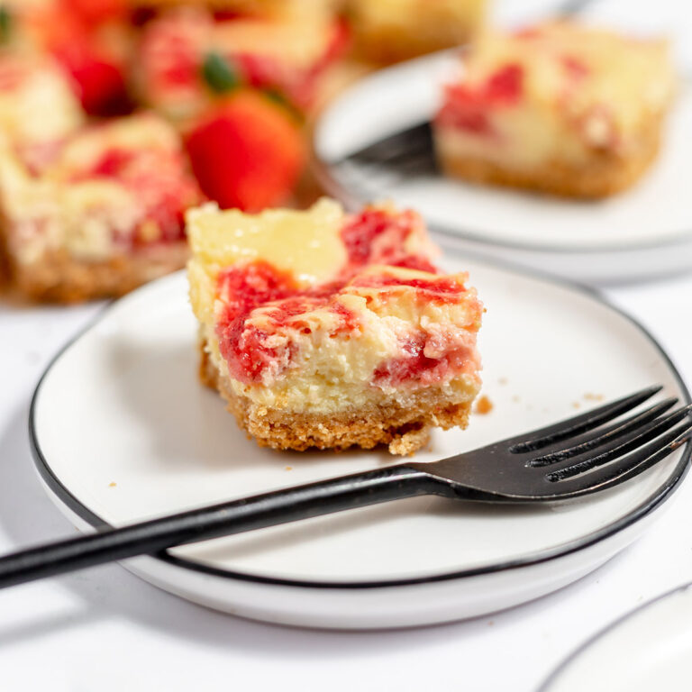 Strawberry cheesecake bar on a white plate with a fork.