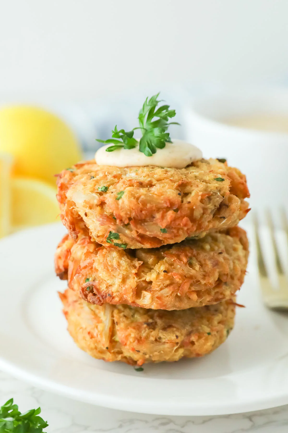 Three crab cakes stacked on a white plate.