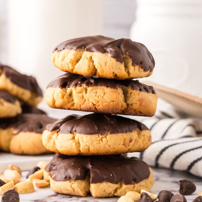Chocolate Dipped Peanut Butter Cookies stacked on the counter.