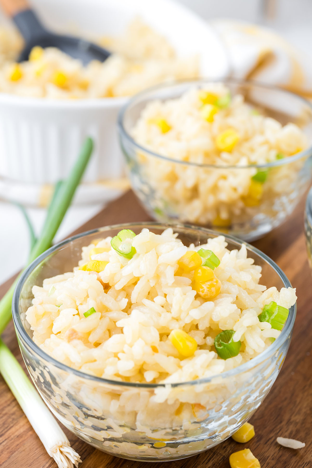 Two bowls with corn rice on a wooden serving board.