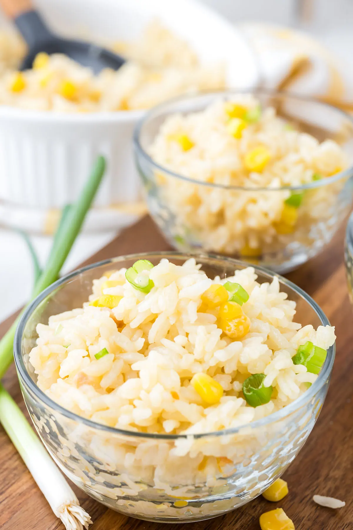 Two bowls with corn rice on a wooden serving board.