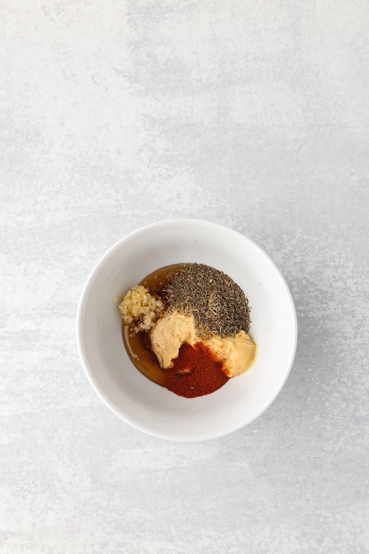 Dijon mustard, honey, minced garlic, dried thyme, and paprika in a small bowl.