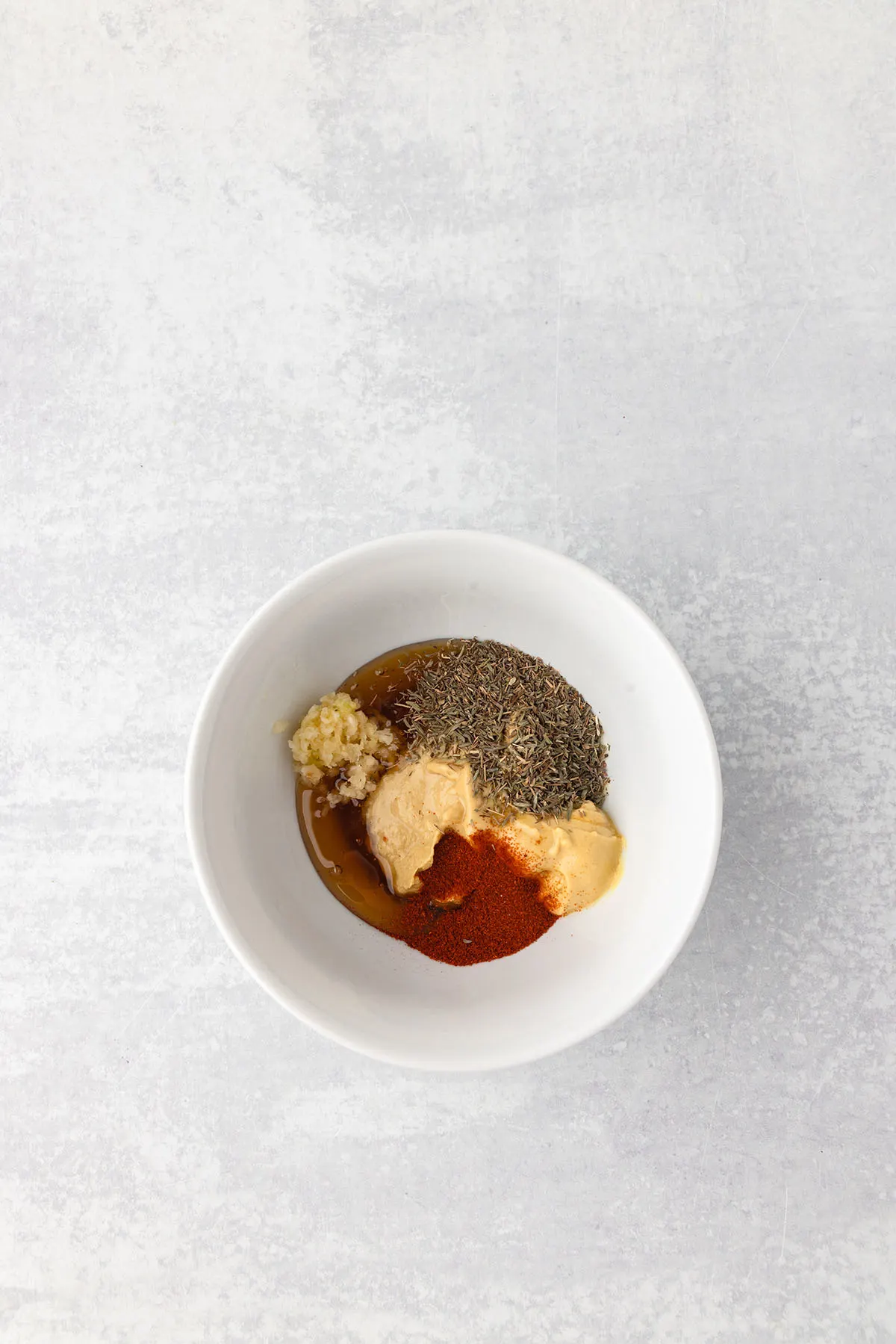 Dijon mustard, honey, minced garlic, dried thyme, and paprika in a small bowl.