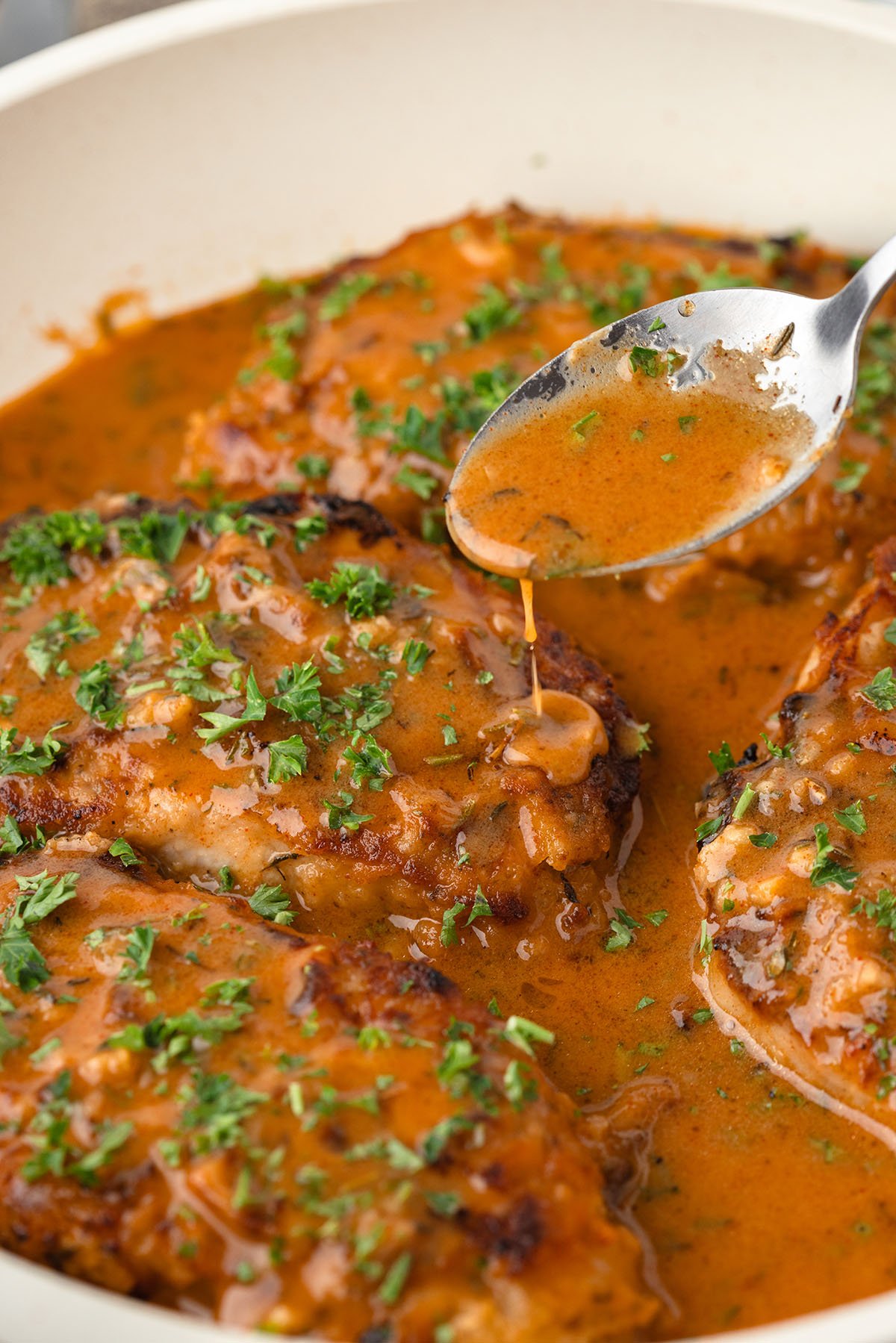 Honey mustard sauce is spooned over pork chops in the skillet.