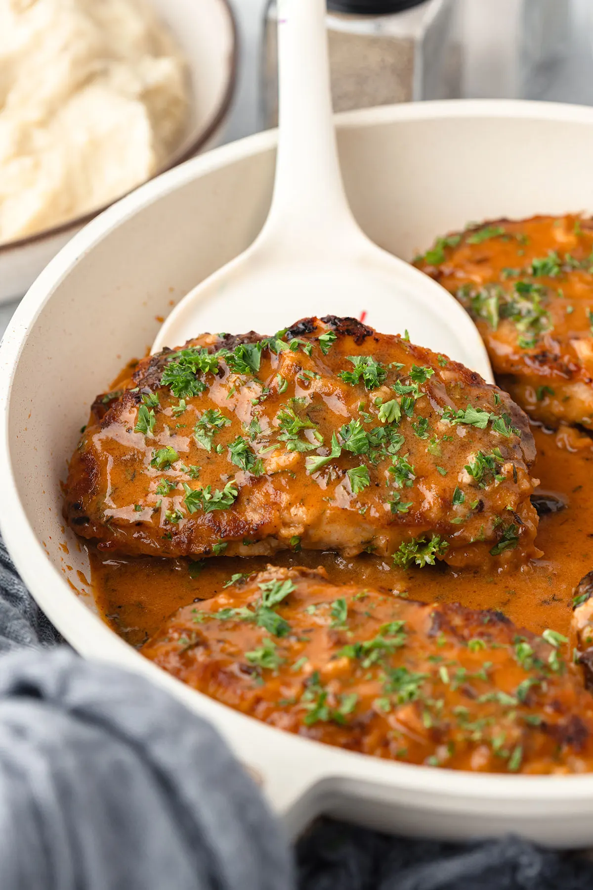 A pork chop on a spatula is removed from the skillet.