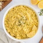 Lemon Orzo served in a white bowl with slices of lemons.