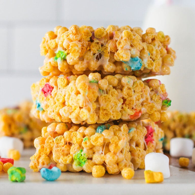 Three Lucky Charms Marshmallow Treats stacked on counter.