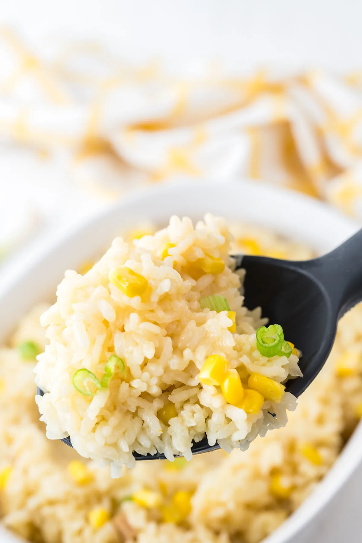 Corn Rice in a black serving spoon over the baking dish.