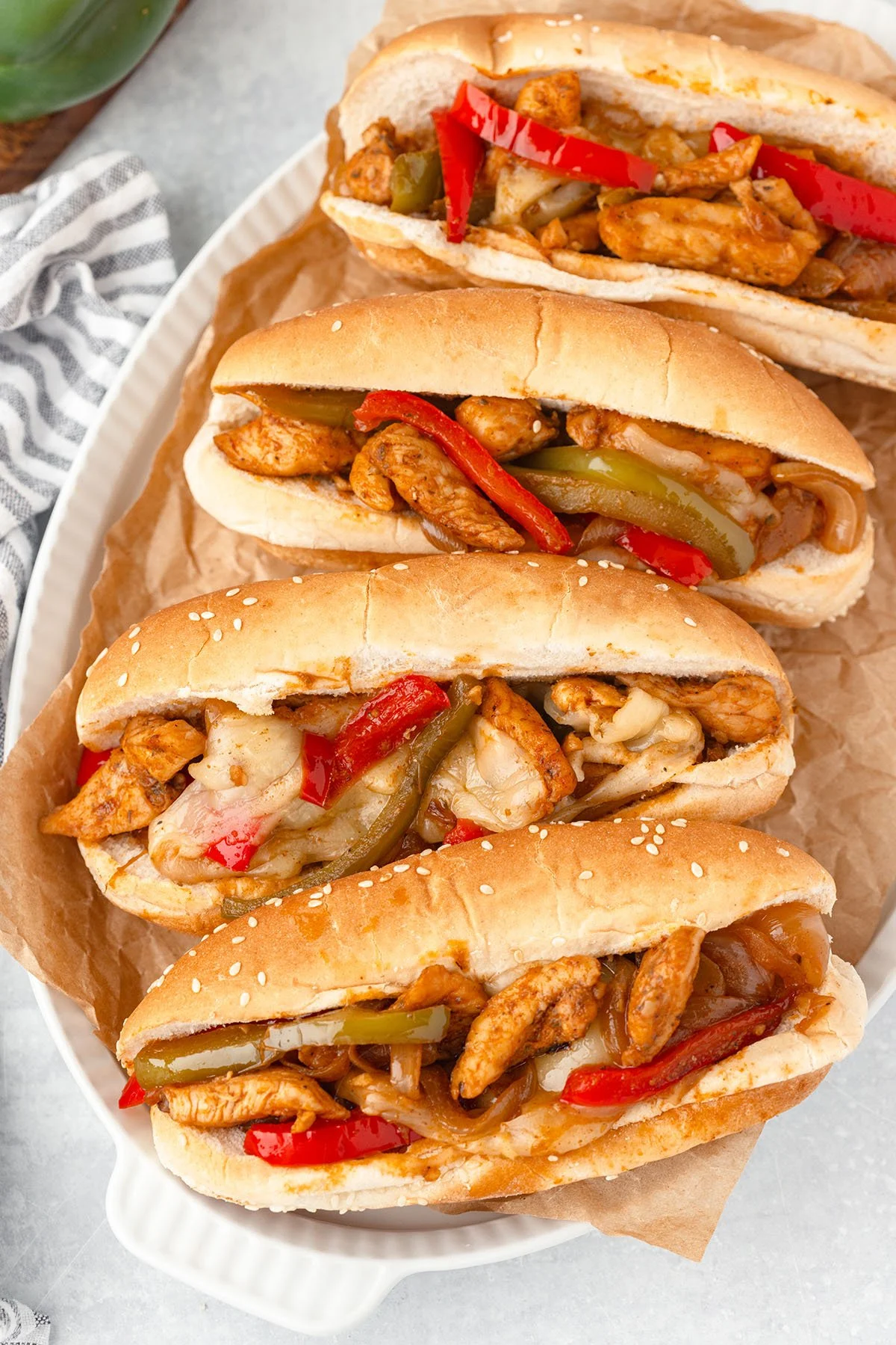 Four Chicken Philly sandwiches on a white serving platter.