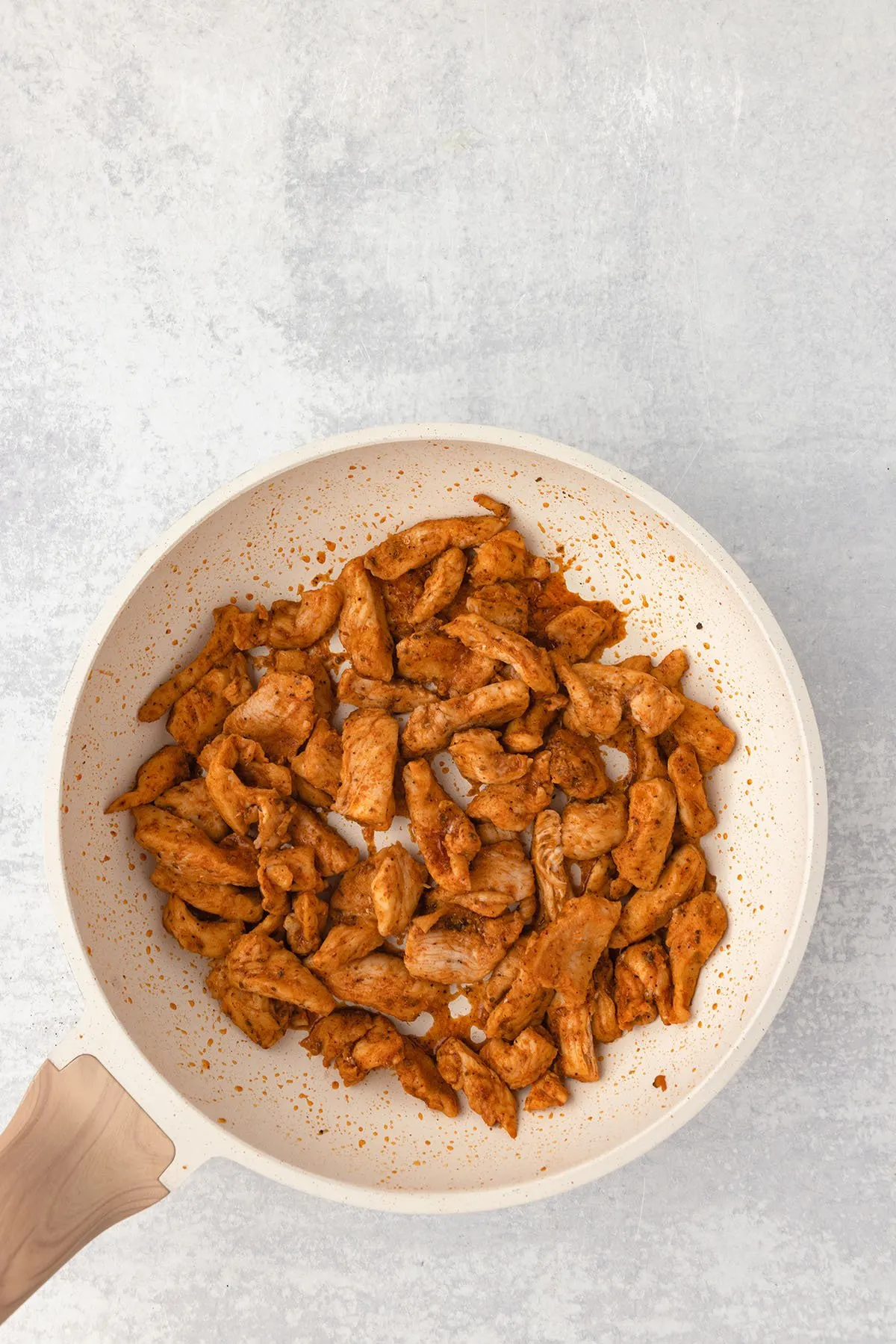 Cooked seasoned chicken slices in a skillet.