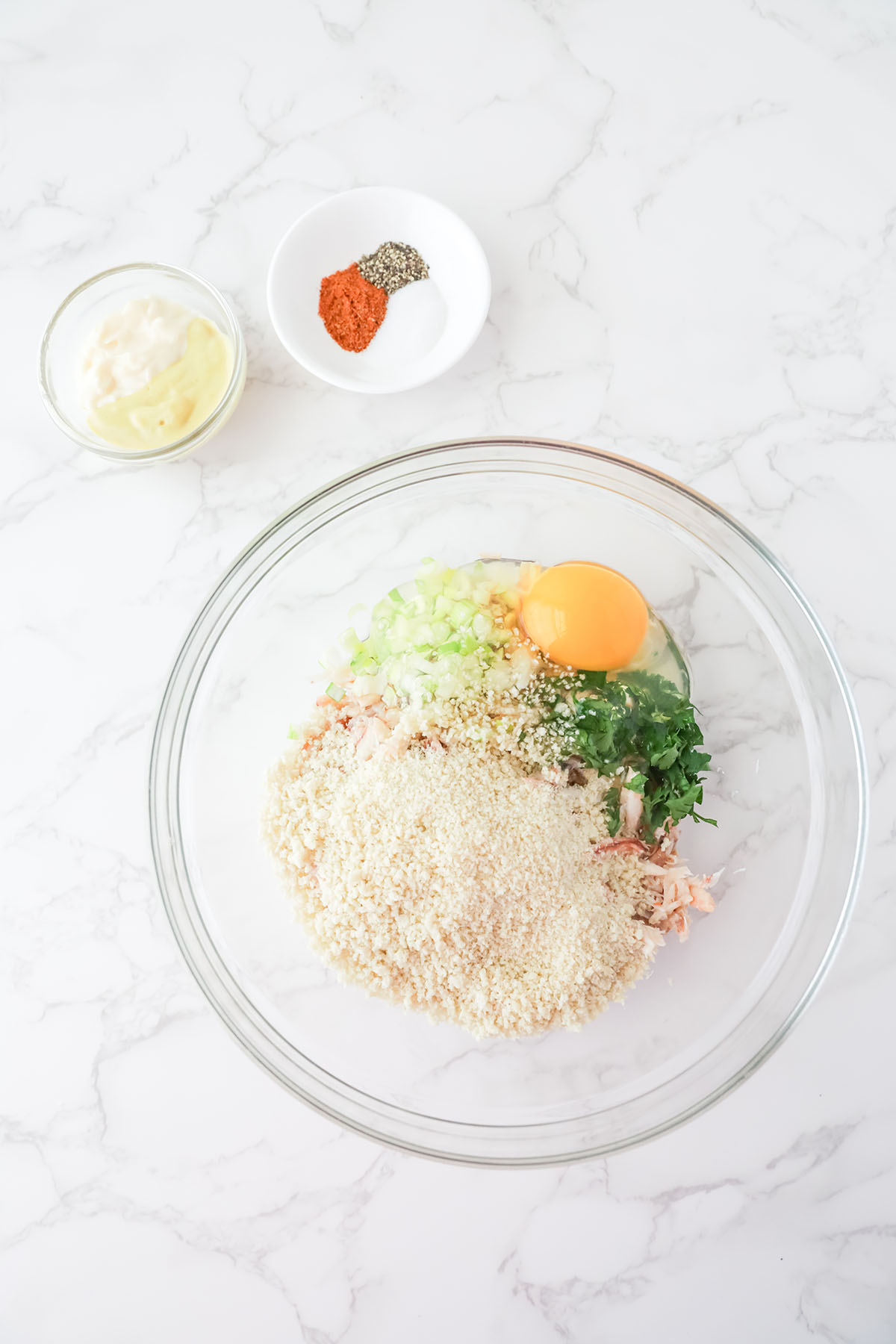 Crab meat, breadcrumbs, egg, parsley, and green onion in a mixing bowl.